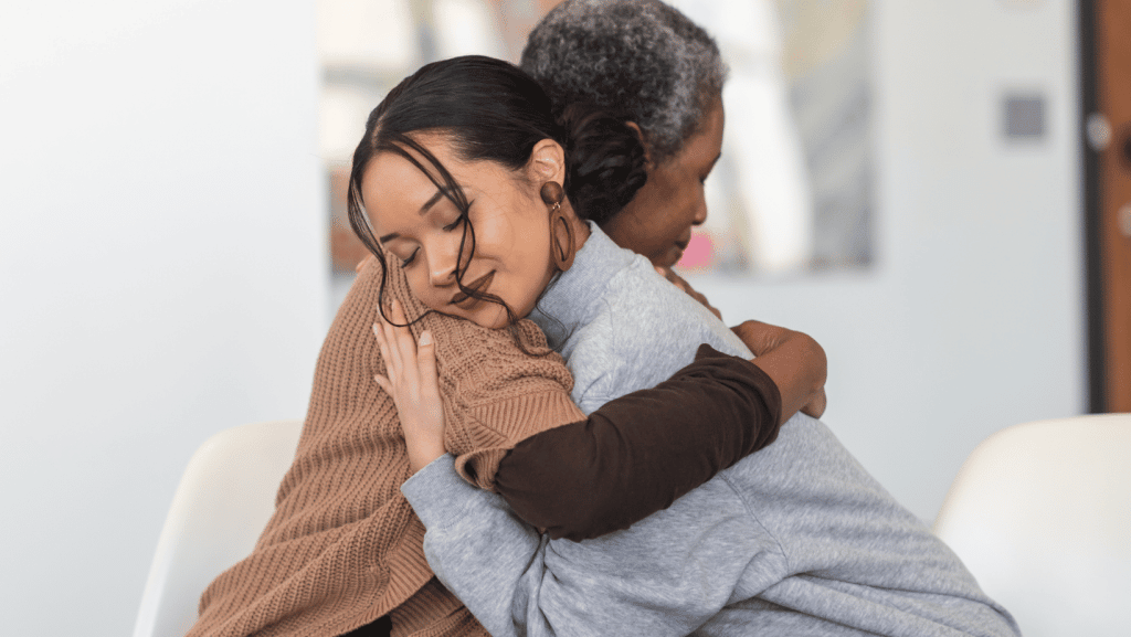 two women hugging eachother at a group therapy session 